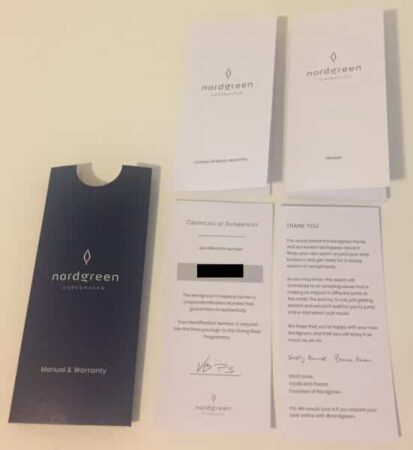An arrangement of Nordgreen Watch Review brand paper items: a manual and warranty booklet, a certificate of authenticity with a blurred-out section, and a thank-you note, all spread out on a pale surface