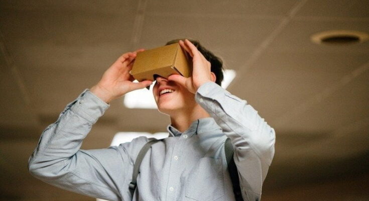 A man looking through a cardboard box of technological gadgets.