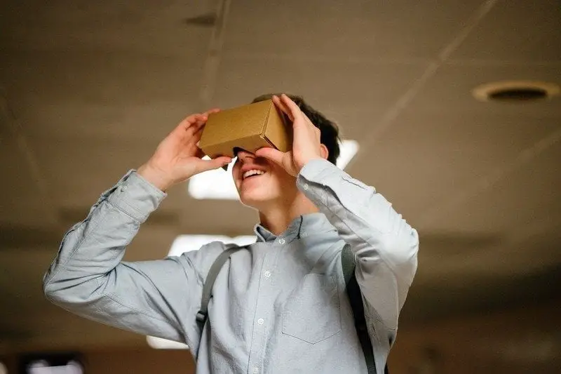 A man looking through a cardboard box of technological gadgets.