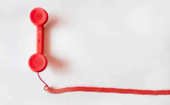 A red telephone receiver with a long cord, ideal for managing spam phone callers list.