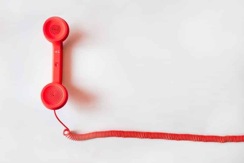 A red telephone receiver with a long cord, ideal for managing spam phone callers list.
