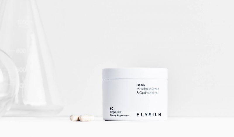 A container of Elysium Health dietary supplement labeled "metabolic repair & optimization" with two capsules beside it, set against a minimalist white background.