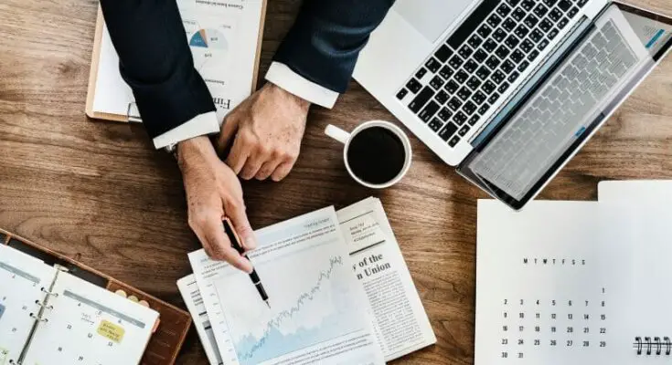 A person holding a pen and looking at a graph on paper illustrating three ways technology can streamline your business for greater success.