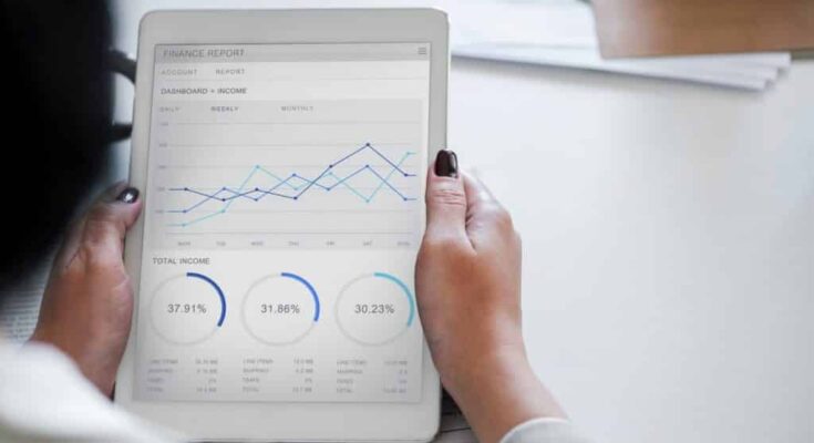 A person explores tech opportunities through a financial report on a tablet, displaying graphs and pie charts, focusing on data analytics.