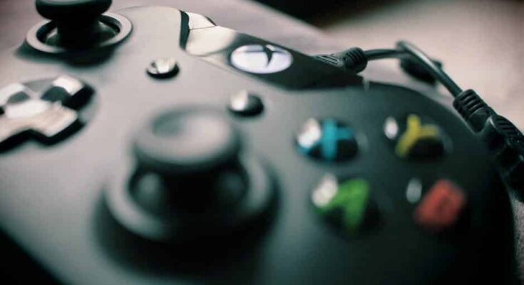 Close-up of a black video game controller with colorful buttons and a plugged-in cable, focused on the left joystick and directional pad, ideal for playing free games.