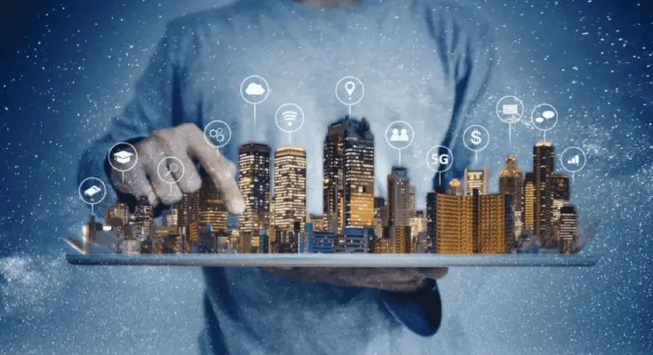 A person in a casual shirt holds a tablet projecting a holographic cityscape with various connected technology icons, symbolizing "How Much Smarter Can Technology Get" concepts against a starry night background.