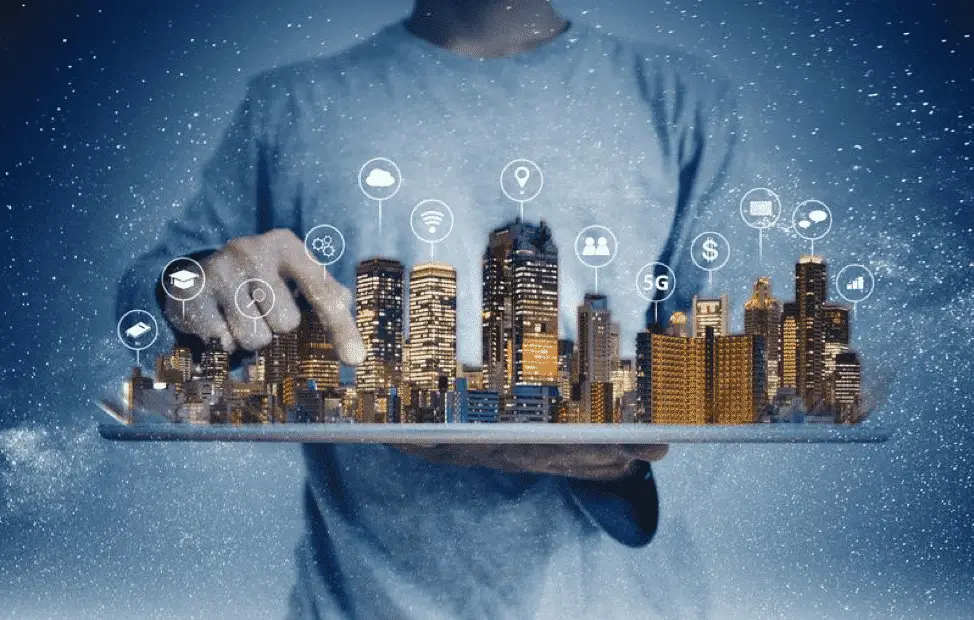 A person in a casual shirt holds a tablet projecting a holographic cityscape with various connected technology icons, symbolizing "How Much Smarter Can Technology Get" concepts against a starry night background.