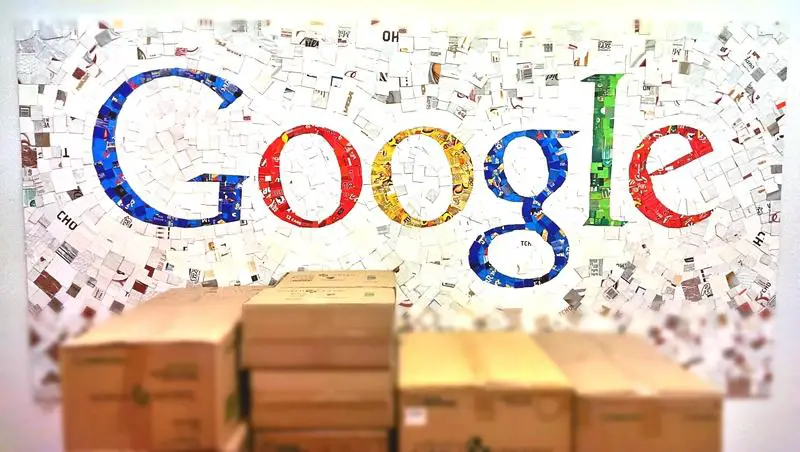A colorful Google Classroom logo made up of various photographs and images on a wall, with stacks of cardboard boxes in the foreground.