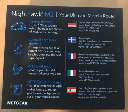 Image of Netgear Nighthawk M2 mobile router packaging. Features include up to 2Gbps speed, durable battery, touchscreen, and WiFi creation. Covers descriptions in various languages and the Net