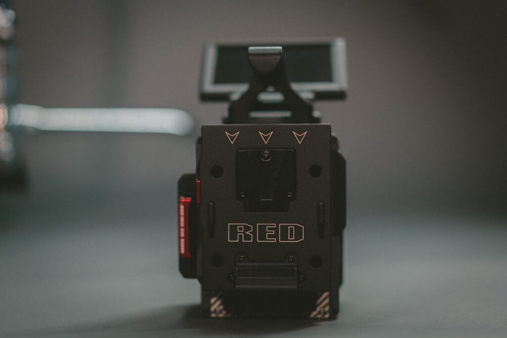 A close-up photo of a red digital cinema camera, focusing on the back of the camera body with the red logo prominently displayed. the background is blurred.