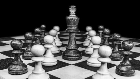 Classic black and white chessboard with a king surrounded by pawns, illustrating strategy and confrontation in a game of chess.