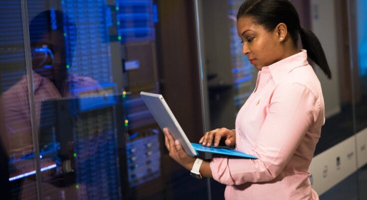 photo of woman holding a gray laptop in front of systems