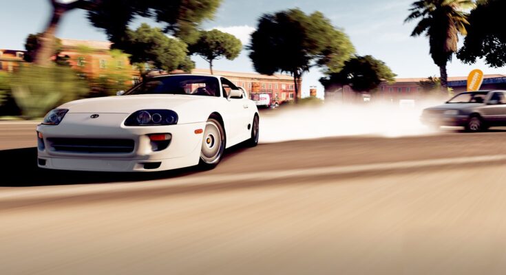 White sports car performing a dynamic drift in a video game setting on a sunny street lined with trees and colorful buildings, creating a trail of tire smoke.