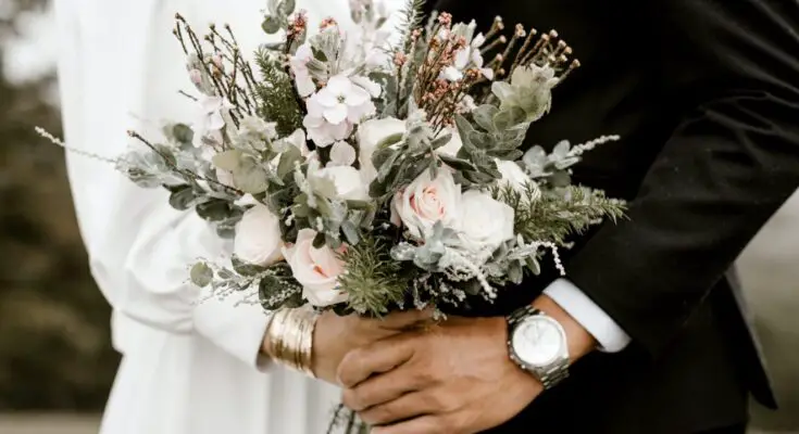 bridge and groom standing while holding flower bouquet