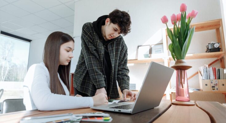 woman in white long sleeve shirt using macbook pro with a man wearing long sleeve