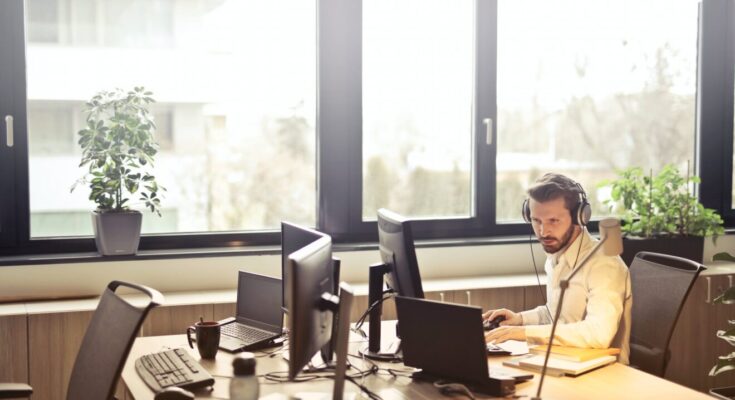 man with headphones facing computer monitor