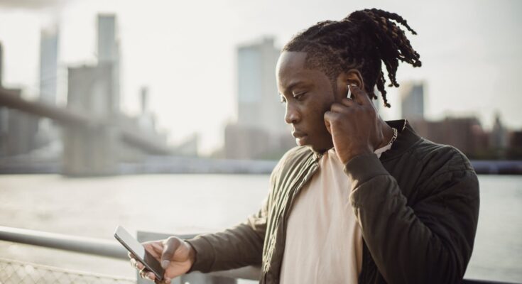 melancholic black man with smartphone listening to music in earphones