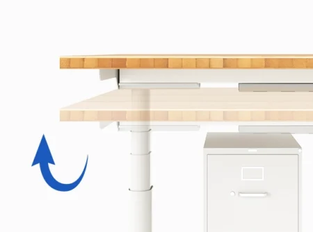 A standing desk with a light wooden top, showcasing the desk being raised, indicated by a blue upward arrow, with a white metal structure and a filing cabinet beneath it.