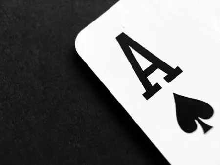 black ace of spaces playing card on a black background and a white card