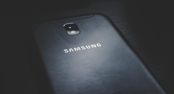 A close-up of a Samsung smartphone in a dark setting, optimized for gaming, with emphasis on its rear camera and brand logo illuminated by soft light.