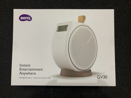 Product box featuring a BenQ GV30 portable projector with a round white body and bronze details, capable of ceiling projection, displayed with the tagline "instant entertainment anywhere.
