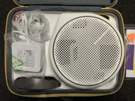 Portable sleep sound machine with ceiling projection and its accessories neatly organized in a zippered case, including a power adapter and cables.