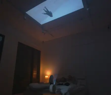 A couple in a dimly lit bedroom with a BenQ GV30 portable projector displaying a scene of a person swimming underwater on the ceiling.