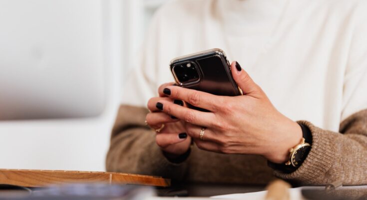 crop woman browsing smartphone at table