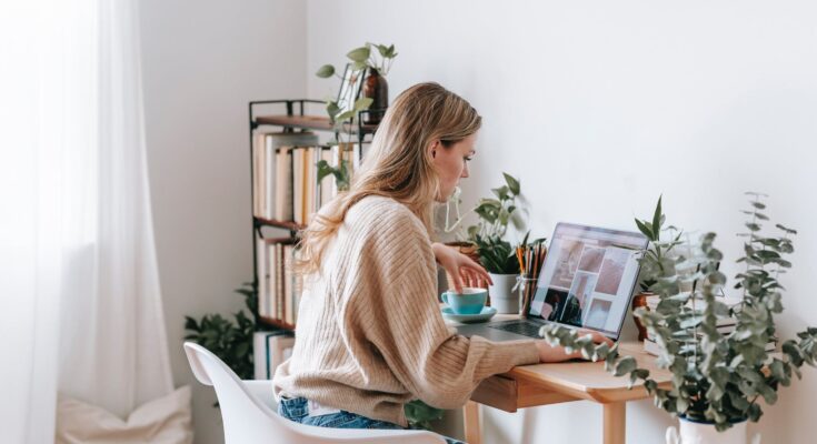 freelancer working on laptop with photos on screen at home