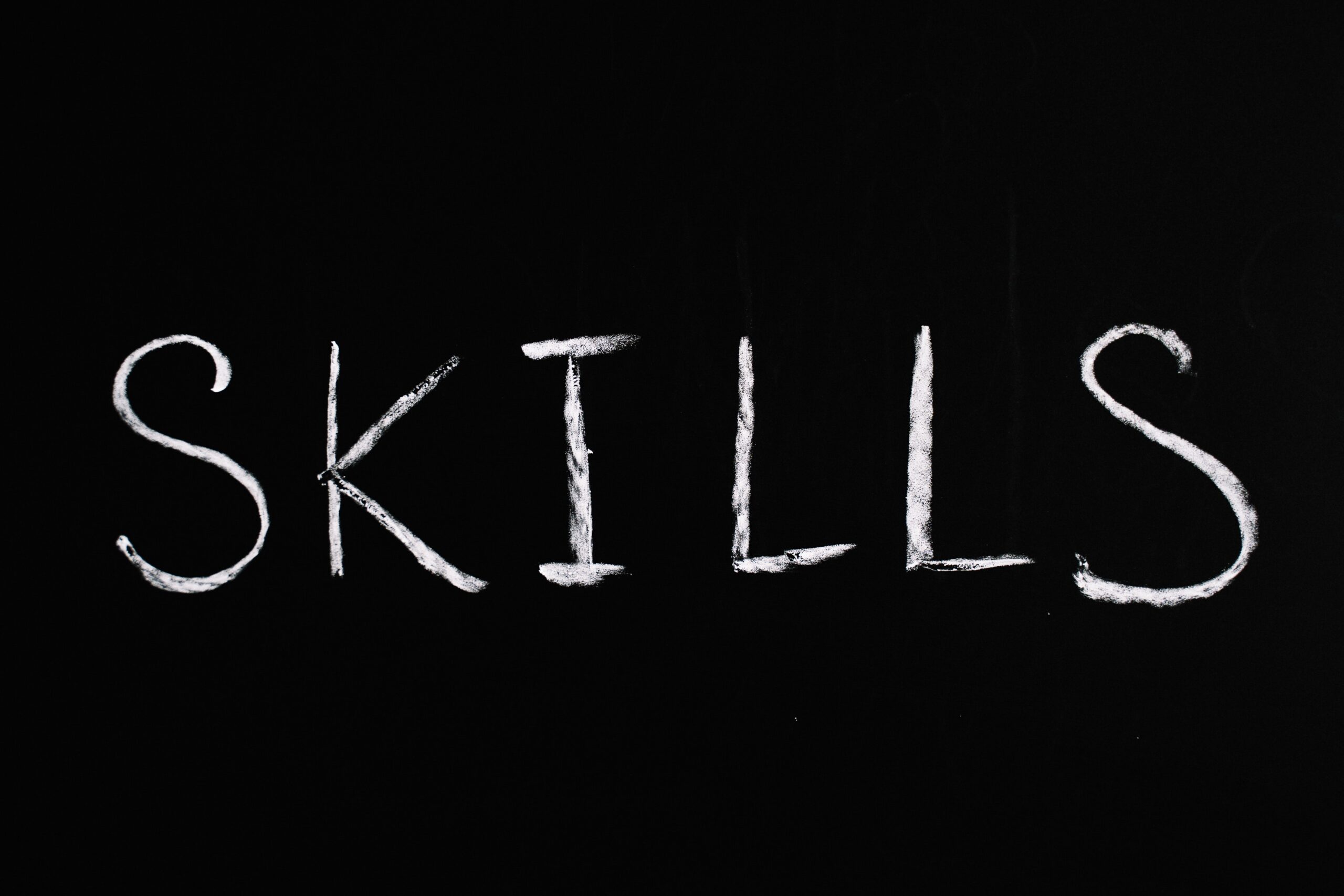 The word "skills" written in white chalk on a blackboard, symbolizing educational, professional, or gaming development concepts.