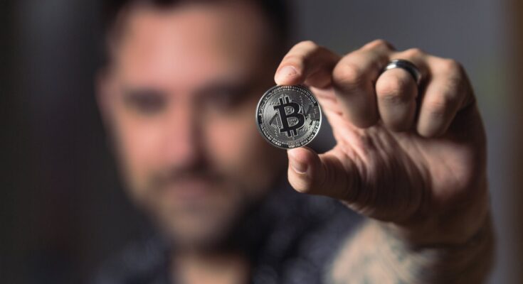 person holding silver bitcoin coin