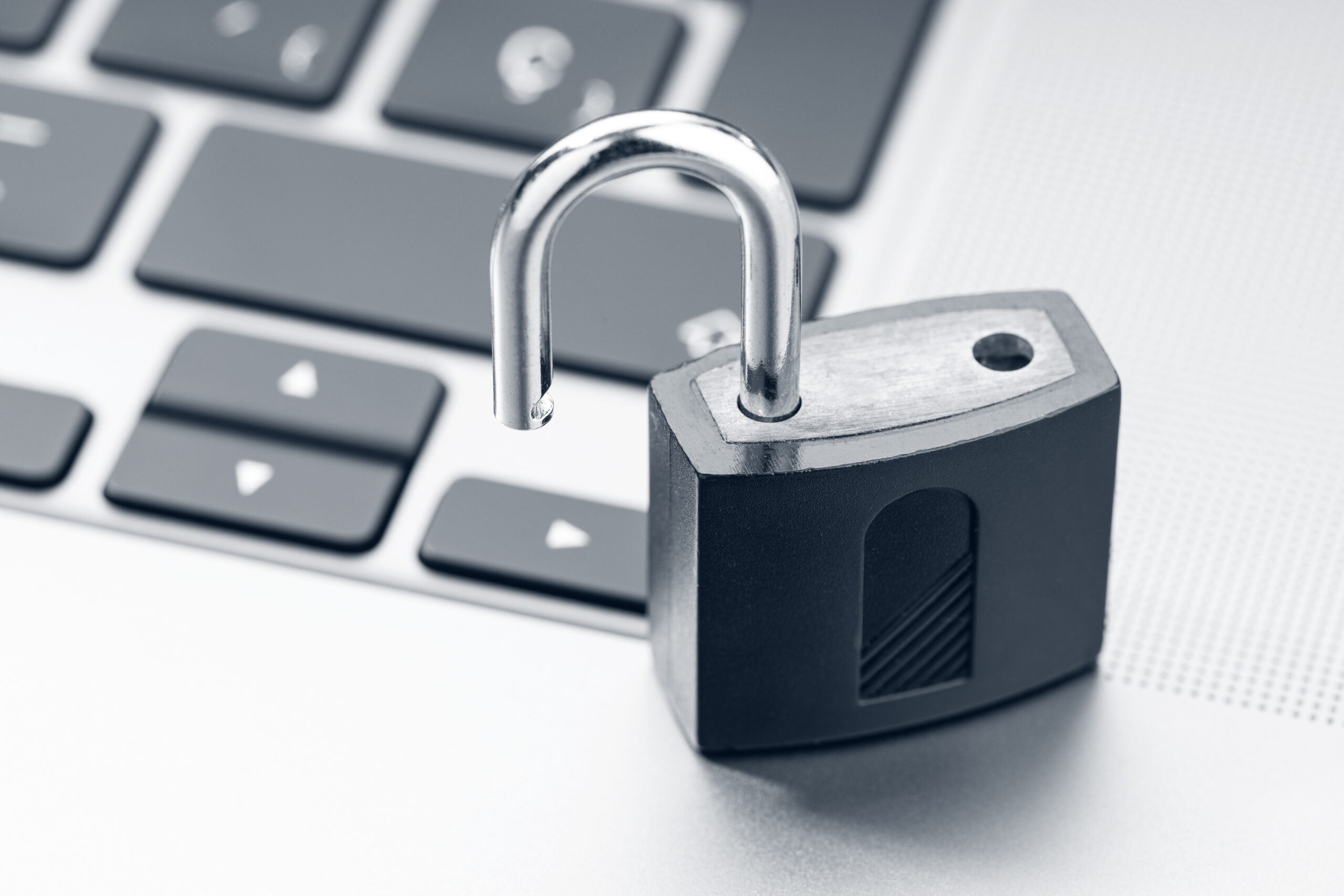 A close-up of an open silver padlock on a laptop keyboard, symbolizing data security in the context of open access publications.