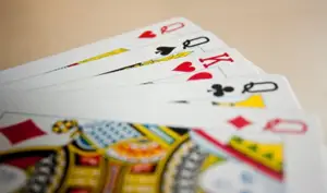 Close-up of a hand of playing cards spread out on a table, featuring myths about bad poker hands including queens and kings, with a focus on intricate details.