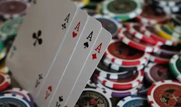 Four aces fanned out with colorful poker chips blurred in the background on a table, challenging myths about bad poker hands.