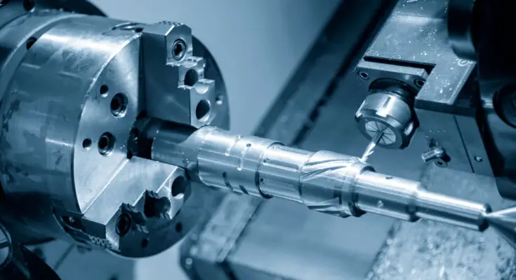 A close-up of a cnc turned lathe machine at work, precision machining a metal rod with blue monochromatic lighting.