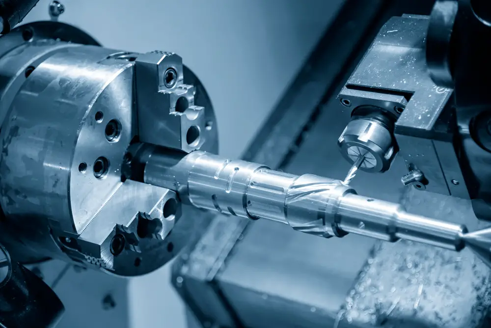A close-up of a cnc turned lathe machine at work, precision machining a metal rod with blue monochromatic lighting.