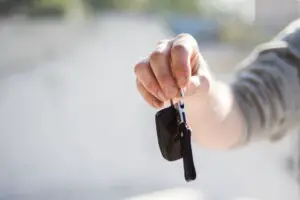 person in grey shirt handing keys