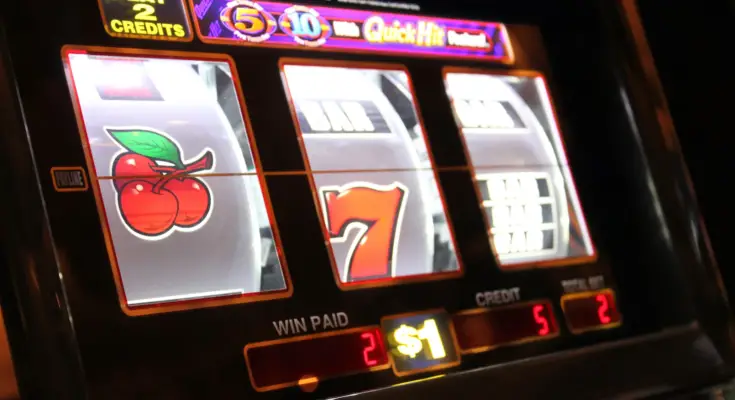 A vibrant Call Slots machine displaying cherry and lucky seven symbols on its reels, highlighting the play credits and winnings on a dimly lit casino floor.