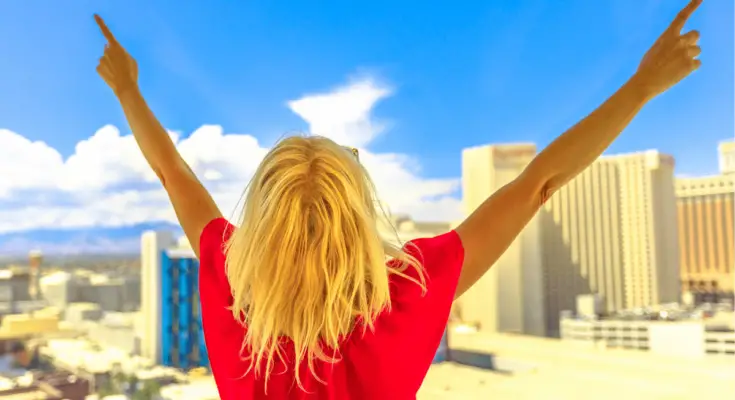 woman celebrating at window over looking large buildings