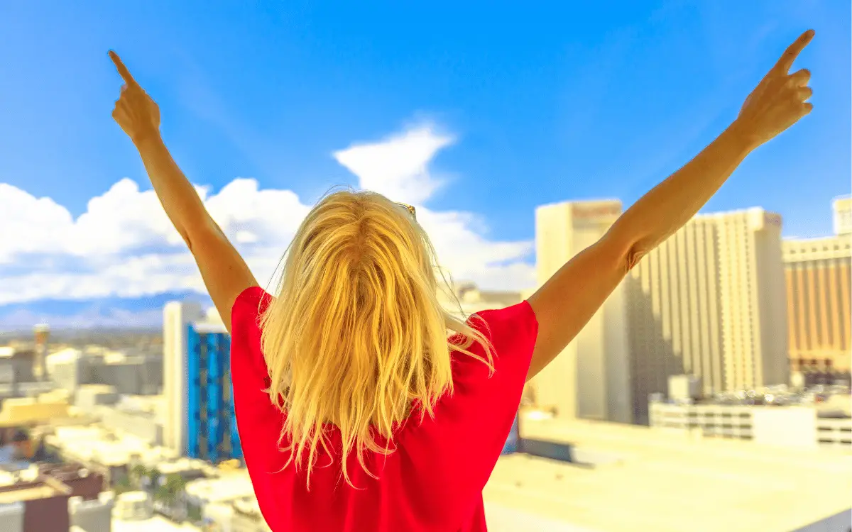 woman celebrating at window over looking large buildings