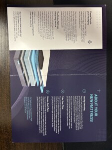 An open promotional brochure on a table, displaying text and graphics about Simba mattresses, featuring a stylized, abstract architectural design.