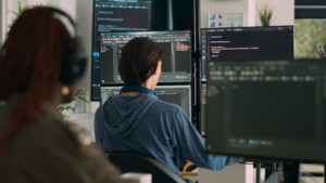 a woman sitting in front of several computer screens