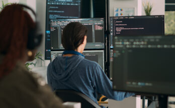 a woman sitting in front of several computer screens