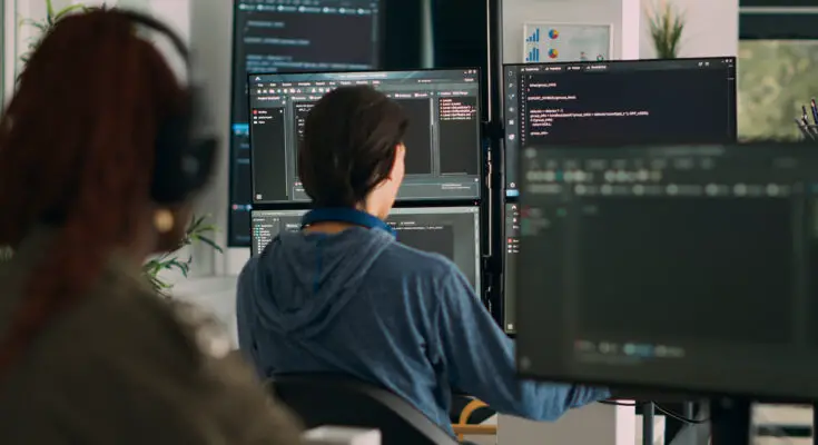 a woman sitting in front of several computer screens