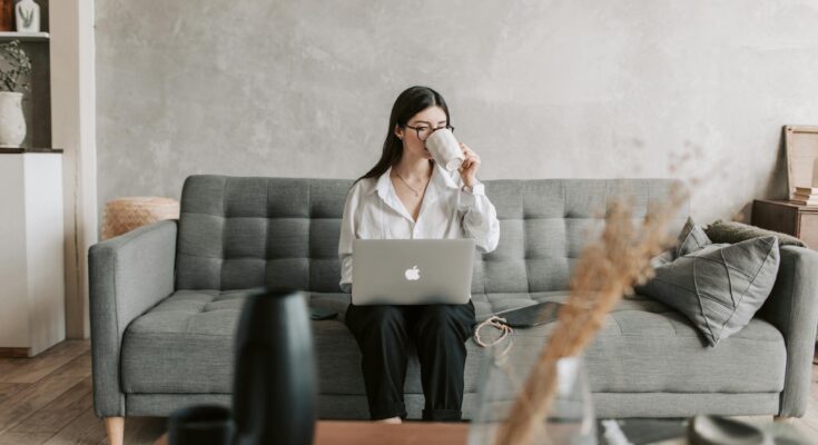 Woman Drinking Coffee While Working With Laptop